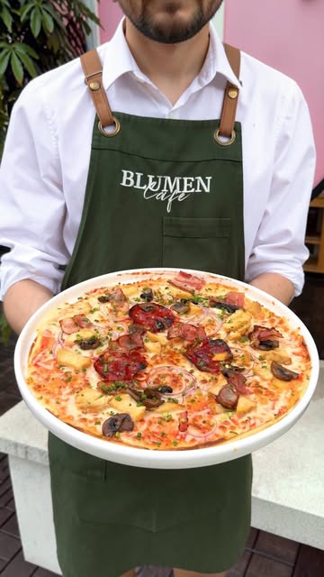 Große belegte Pizza, serviert in der Blumen Café Schürze