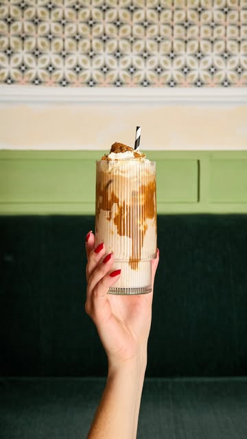 Eiskaffee mit Karamell im geriffelten Glas vor grüner Wand